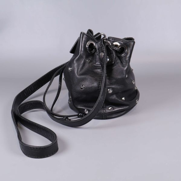 Bakre sida av svart bucket bag med nitar och axelrem