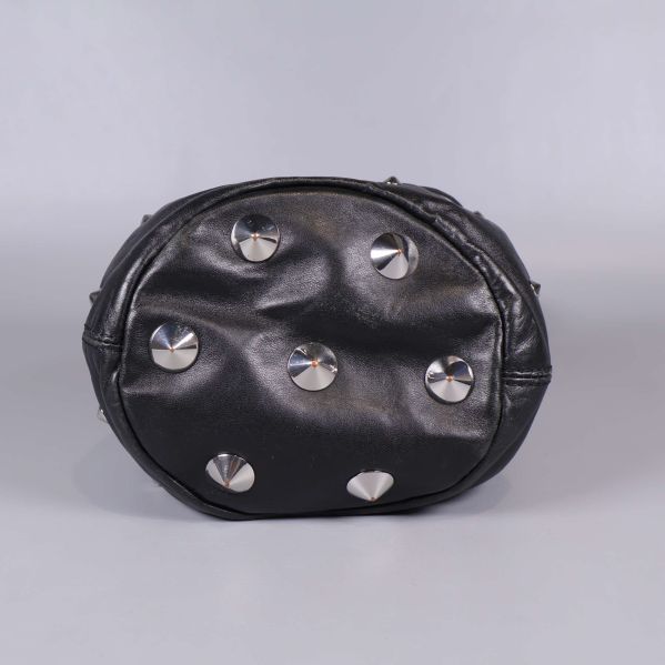 Botten på svart bucket bag med silverfärgade nitar