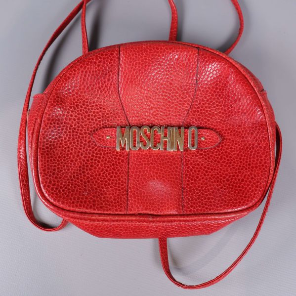 Framsida av röd Moschino-väska med guldfärgad logotyp