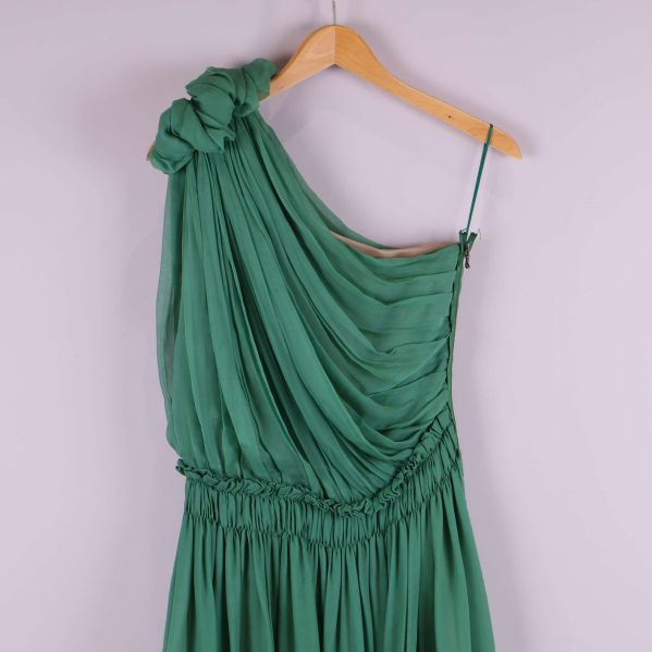 Övre del av grön klänning med blomdetalj vid axeln