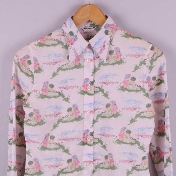 Närbild av skjortans framdel med pastellmönster och blommotiv