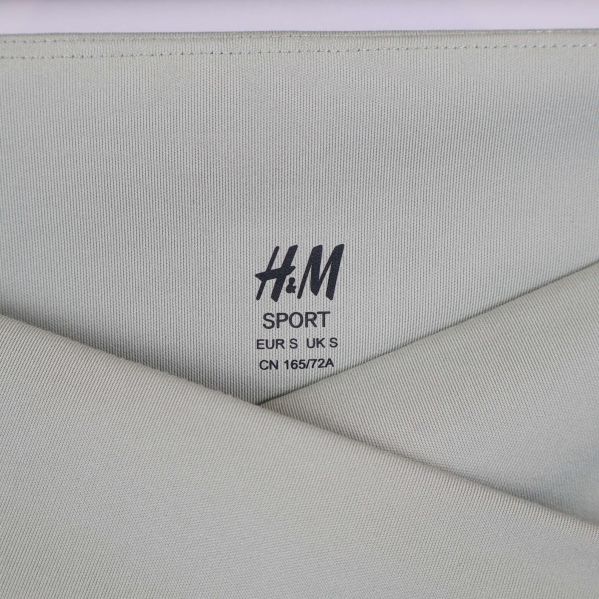 Närbild på h&m sport logga och korsad midjesöm