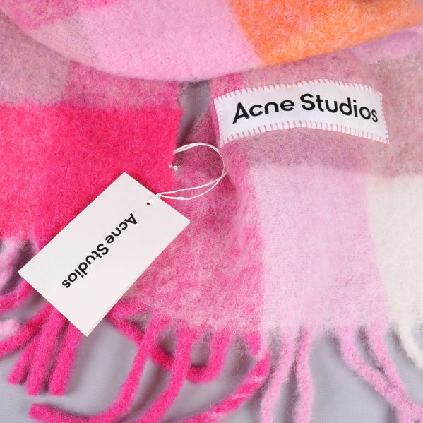 Närbild på Acne Studios-märke och etikett på färgrik halsduk