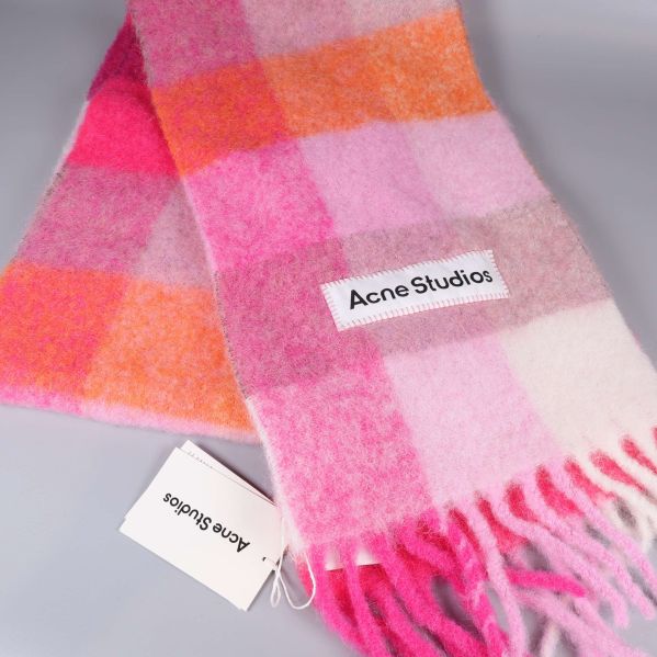 Närbild på rutigt mönster och fransar på halsduk i rosa och orange