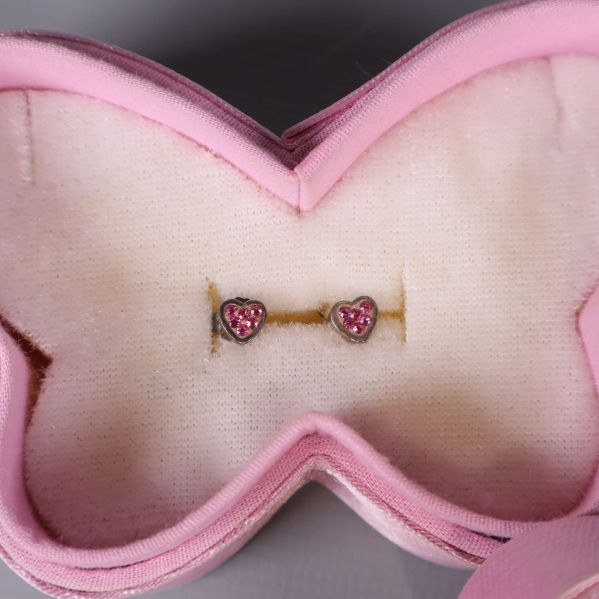 Närbild på hjärtformade örhängen i rosa smyckesask