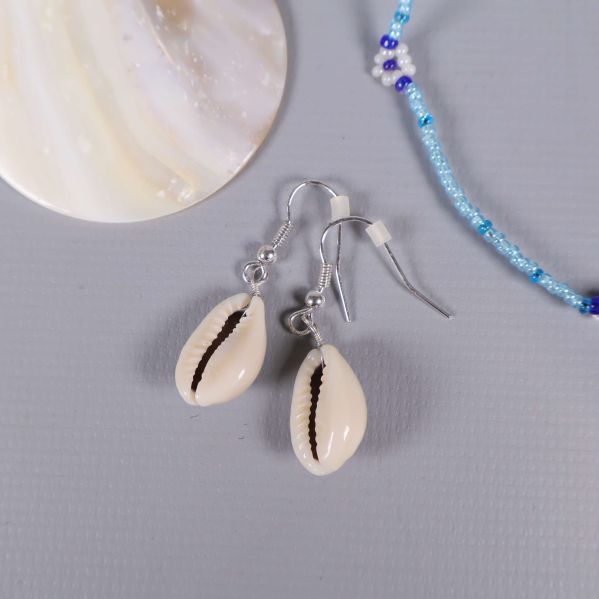 Närbild på örhängen med vita snäckor och silverkrokar