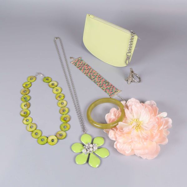 Set med pastellfärgade accessoarer och smycken utlagda på grå bakgrund