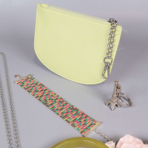 Närbild på litet ljusgult fodral, mönstrat armband, och ringar