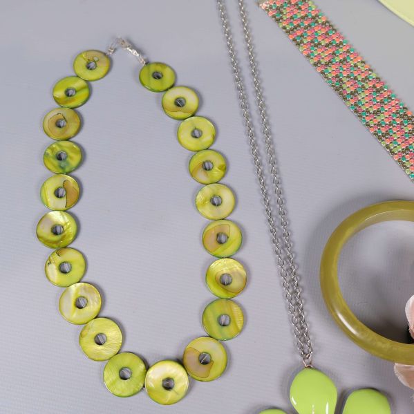 Närbild på halsband med gröna skivor och metallkedja