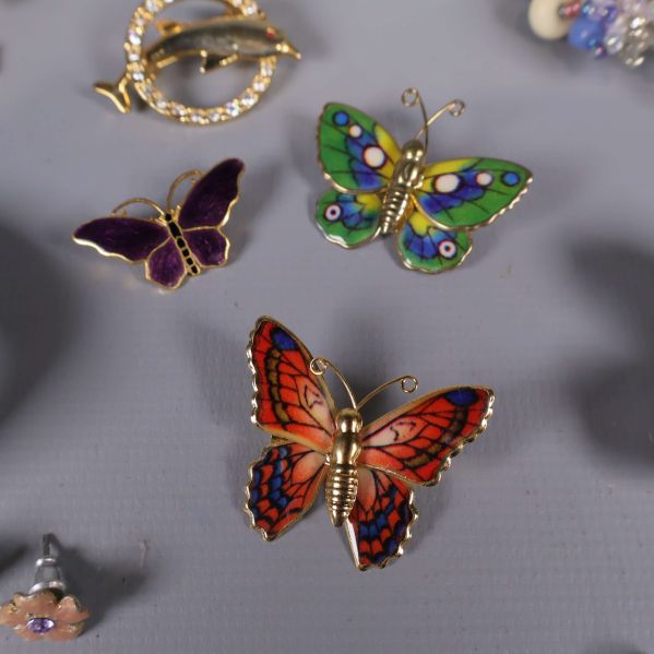 Flerfärgade fjärilsbroscher i orange, lila och grönt