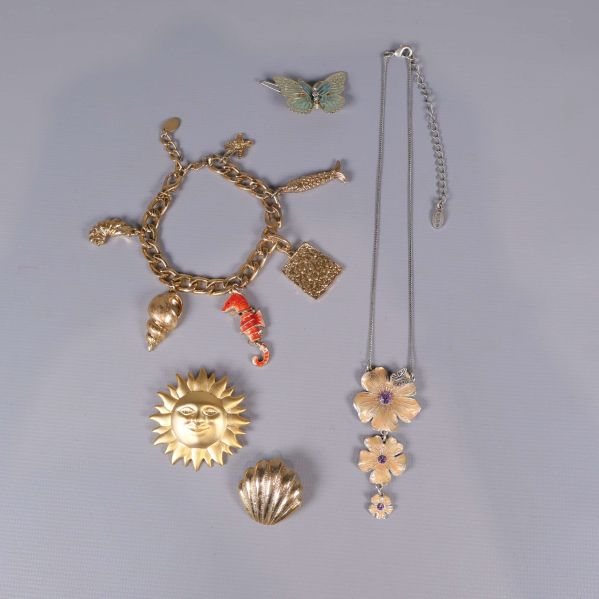 Flera smycken med sol, snäcka, blomma, fjäril och armband med berlocker