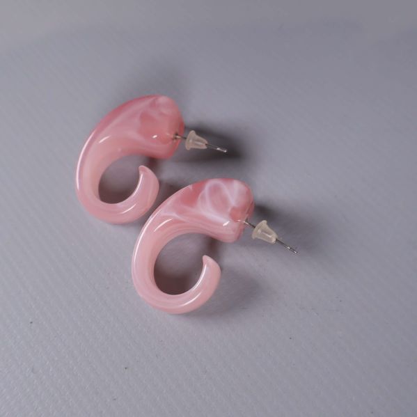 Två runda örhängen i rosa akryl från sidan