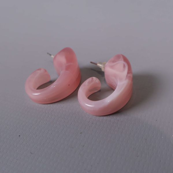 Närbild på swirlmönstrade rosa örhängen