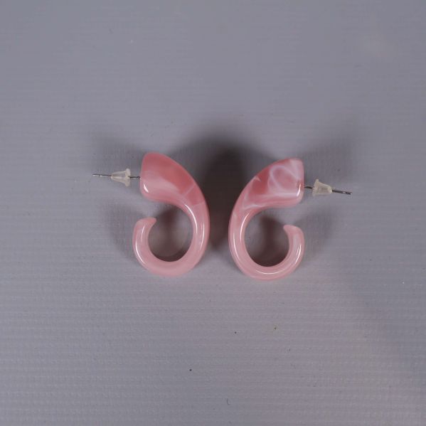 Rosa örhängen parade på ljus bakgrund ovanifrån