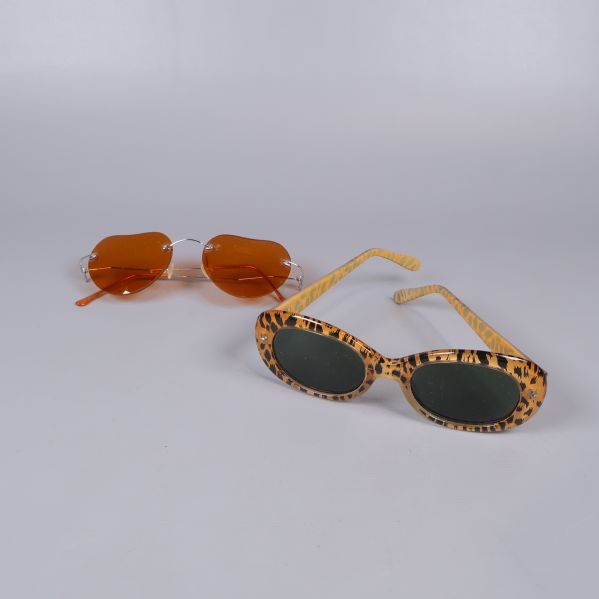 Två par solglasögon, ett med djurmönster och ett med orange glas