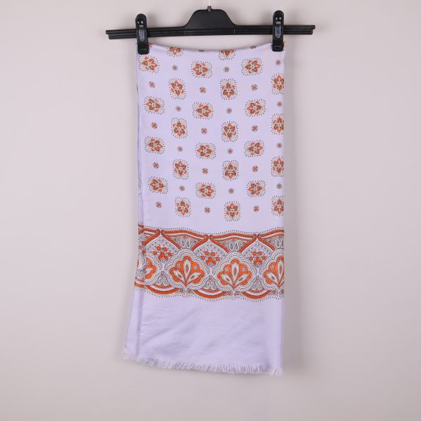 Ljus sjal med orange blommönster och bård hänger på galge