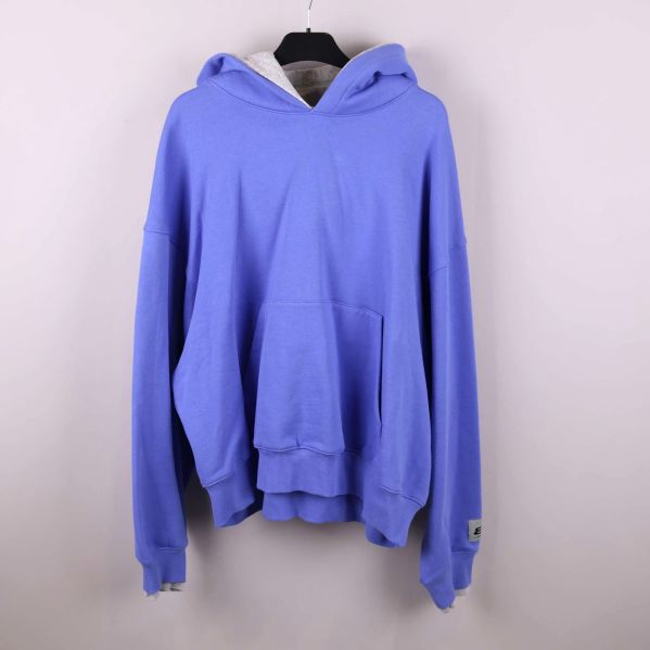 Blå oversized hoodie med huva och magficka hängande på galge