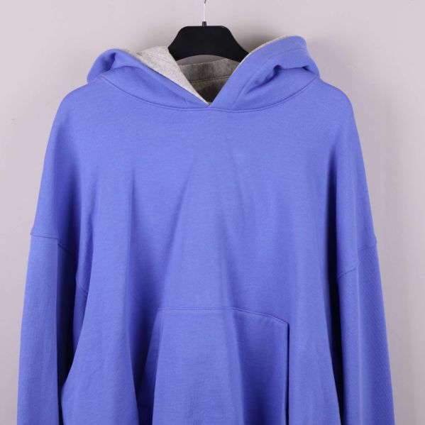 Framstycke av blå hoodie med synlig magficka och huva