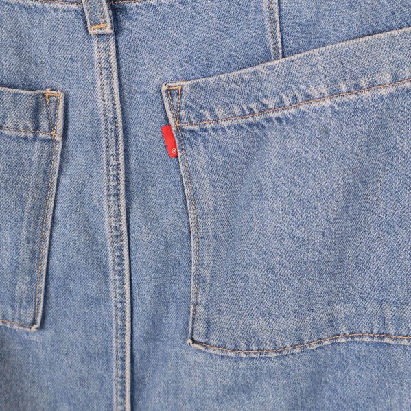 Närbild på bakfickor och röd etikett på jeanskjol
