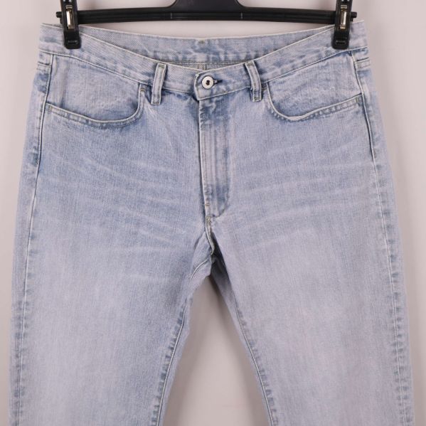 Närbild på jeansens framsida med knäppning och fickor