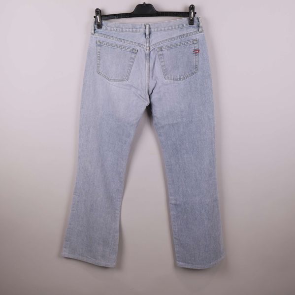 Baksidan av ljusblå jeans med fickor och knappdetalj