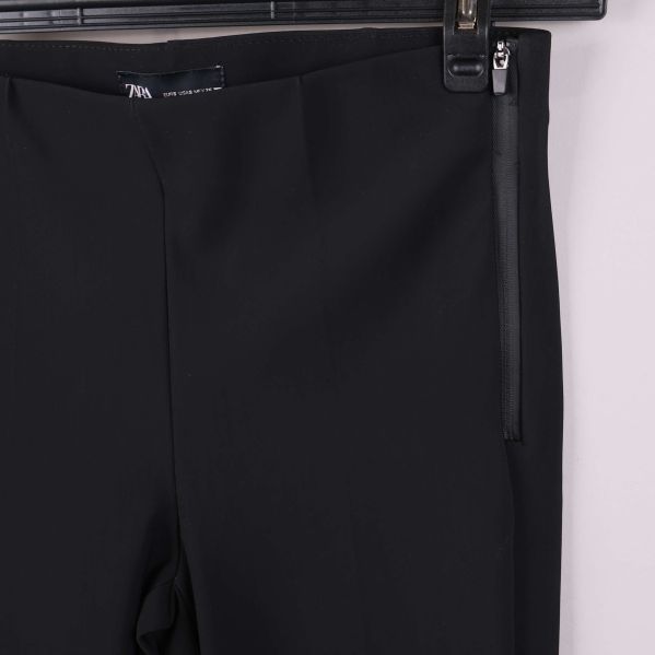 Närbild på sidodragkedja vid midjan på svarta byxan