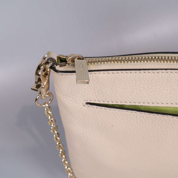 Närbild på guldfärgad kedja och dragkedjetag med präglad text