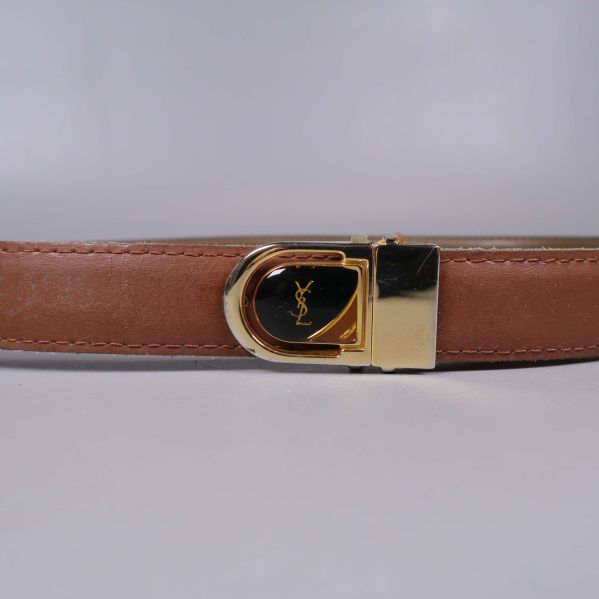 Närbild på bältespänne med YSL-logga i guld
