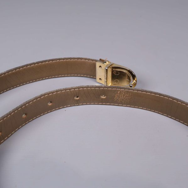 Guldfärgat spänne och ljusbrun insida på bältet