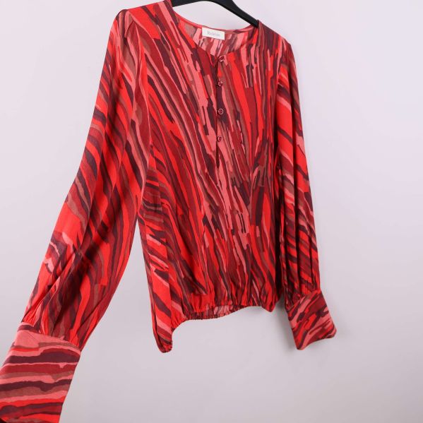 Röd mönstrad blus sedd från sidan på galge