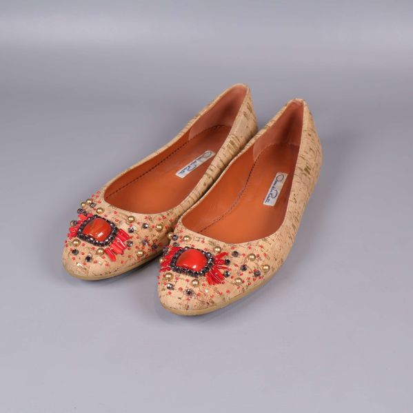 Ett par beige ballerinaskor med dekorstenar framtill