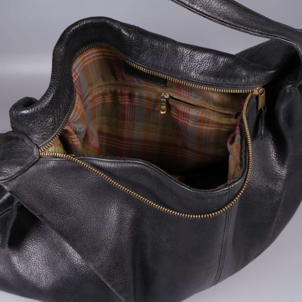 Öppen väska visar rutigt innefoder och trasig dragkedja