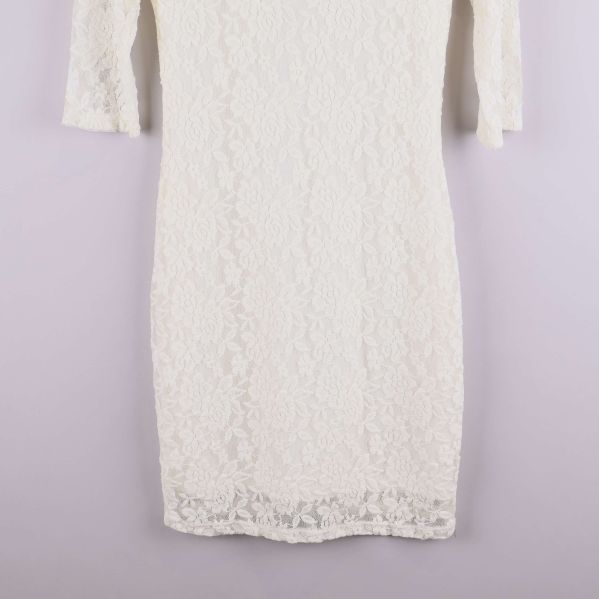 Närbild på nederdelen av vit spetsklänning