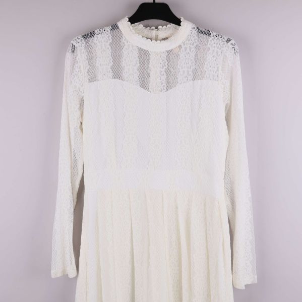 Detaljbild på klänningens spets, överdel och ärmdesign