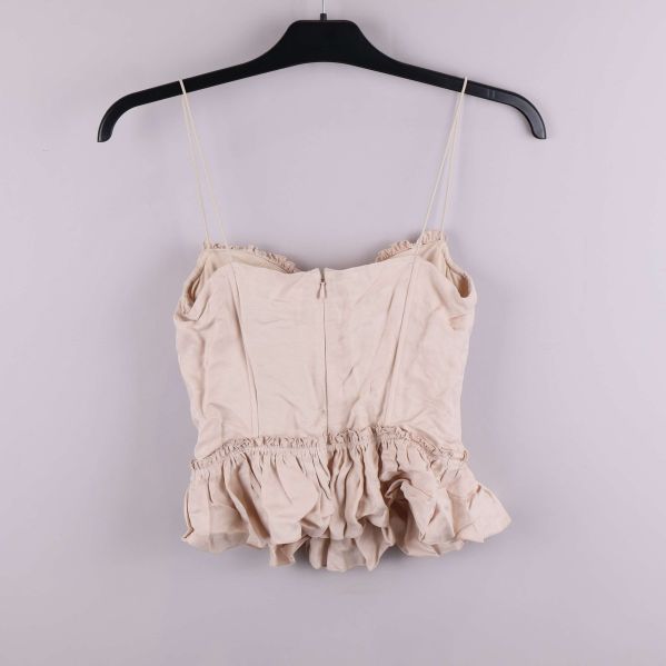 Baksidan av ljusbeige bustier med volang, dragkedja synlig