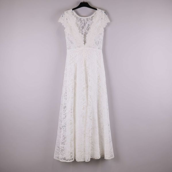 Vit lång spetsklänning upphängd på galge, helbild bakifrån