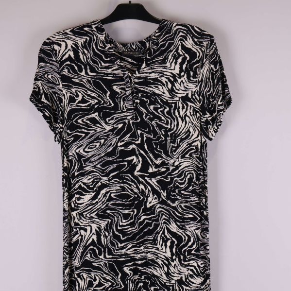 Detaljbild på överdelen av svartvit klänning med knappslå