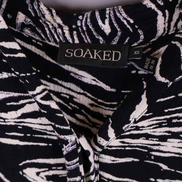 Närbild på Soaked-märke och storleksetikett XS i klänningens halslinning