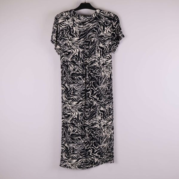 Svartvit mönstrad klänning fotograferad bakifrån på galge