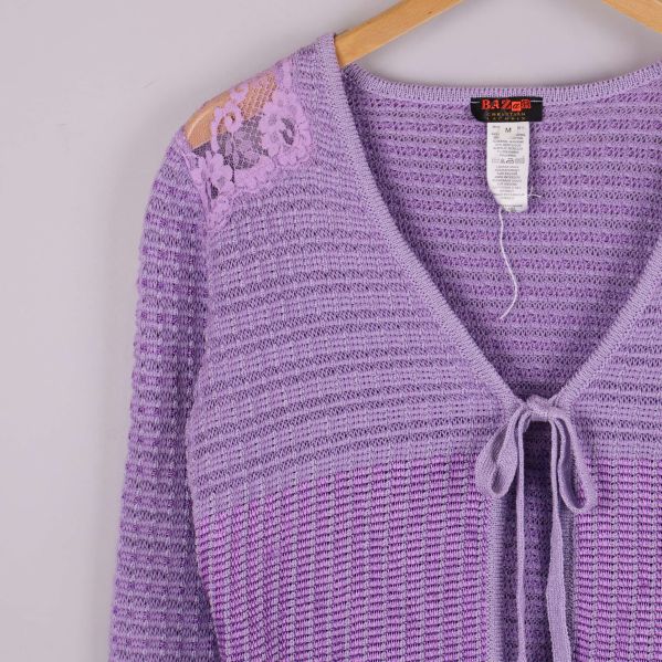 Närbild på spetsdetalj och stickat mönster samt etikett i nacken