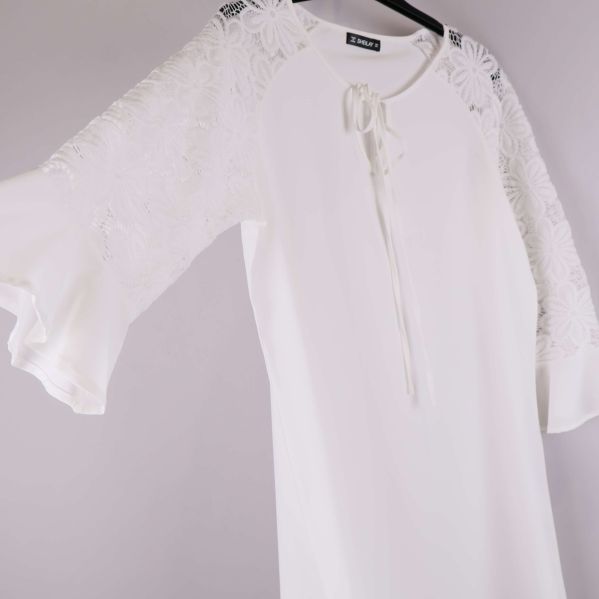 Detalj av klänningens spetsärmar och volangkant