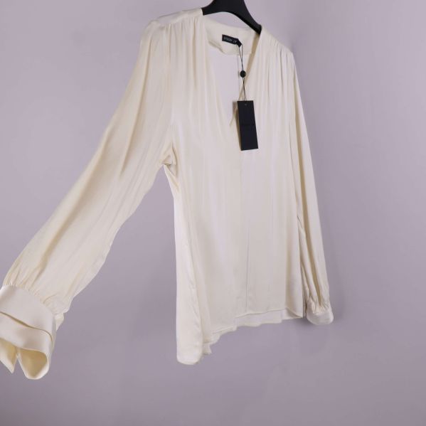 Ljus blus snedvy med markerade manschetter och ledig passform