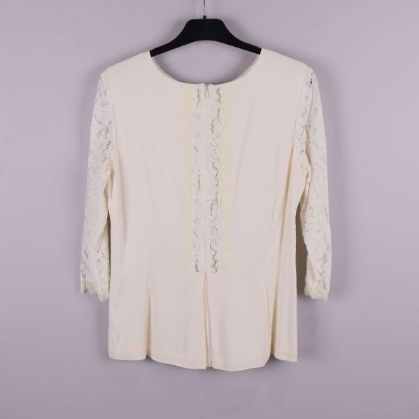Baksida av ljus spetsblus med dragkedja och spetsdetalj