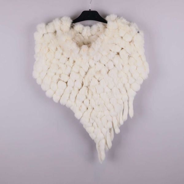 Poncho med tofsar i en enda ljus färg på galge