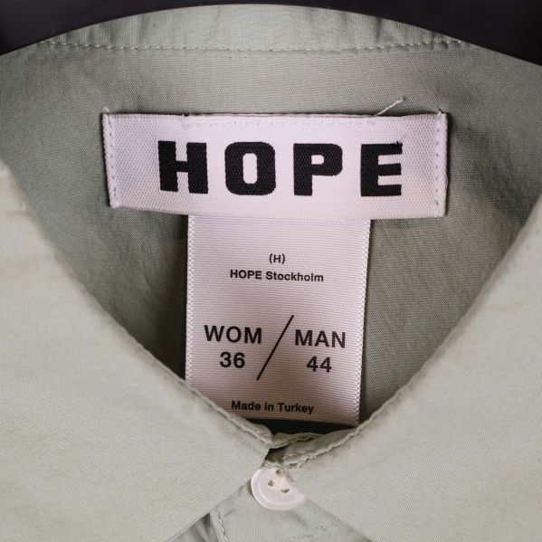 Närbild på HOPE-märke och storleksetikett inuti skjortan