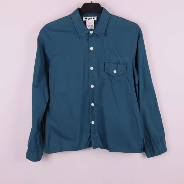 Blå skjorta med vita knappar och bröstficka