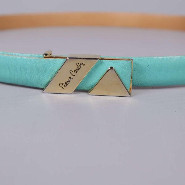 Närbild på guldfärgat spänne med Pierre Cardin-logotyp