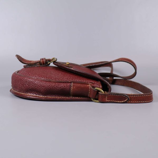 Brun läderväska sedd från sidan på platt underlag