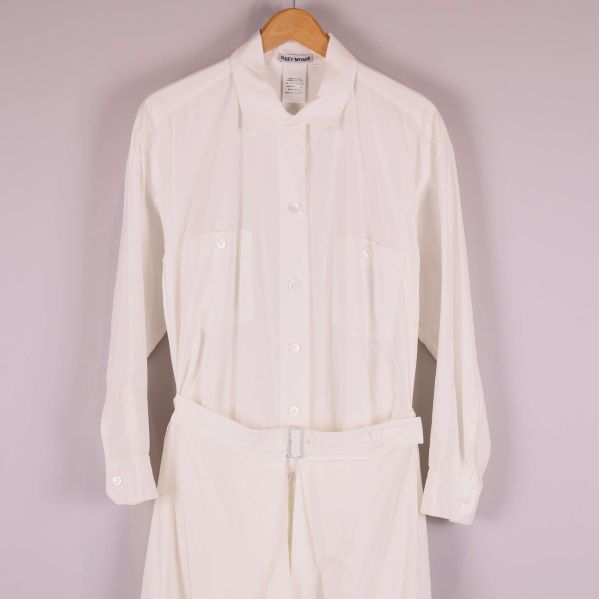 Närbild av övre delen på vit skjortklänning med knappar och fickor