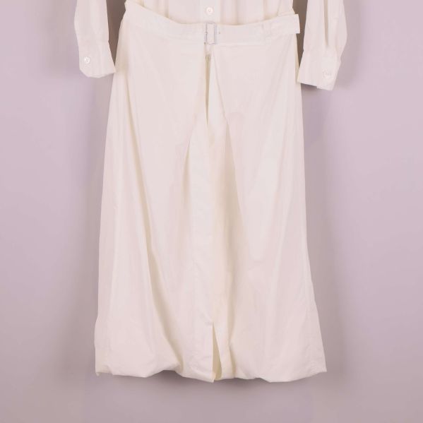 Närbild på kjoldel av vit klänning med bälte i midjan